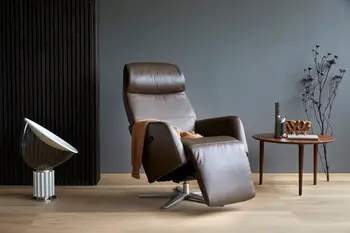 Stressless Scott Relaxsessel in der Farbe Paloma Chestnut mit verstellbarer Relaxfunktion, auf einem Aluminium-Untergestell. Daneben ein runder Holztisch mit Dekor und eine moderne Tischlampe in einem stilvollen Wohnraum.